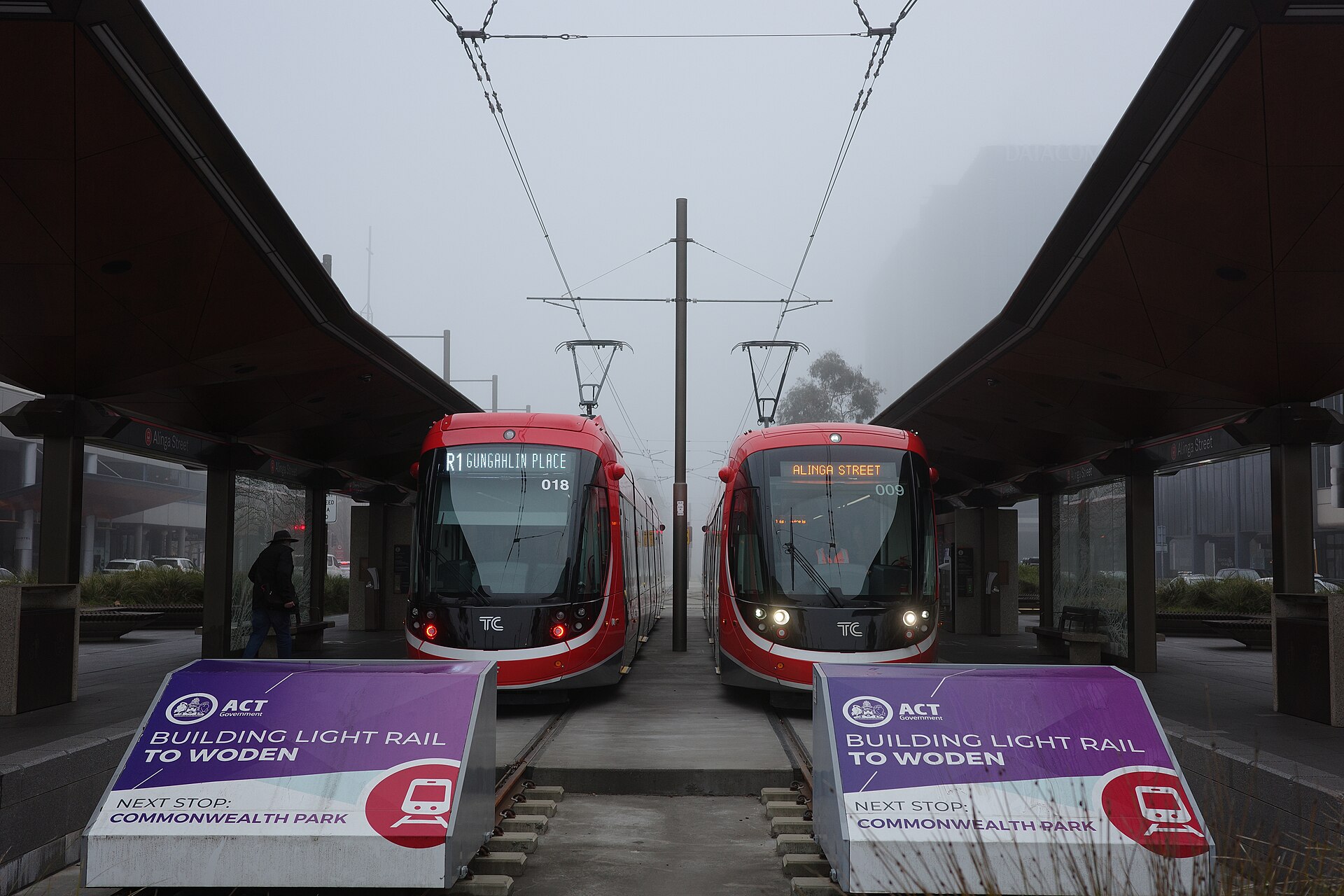 Two light rail vehicles at the Alinga Street stop on a foggy morning in July 2025