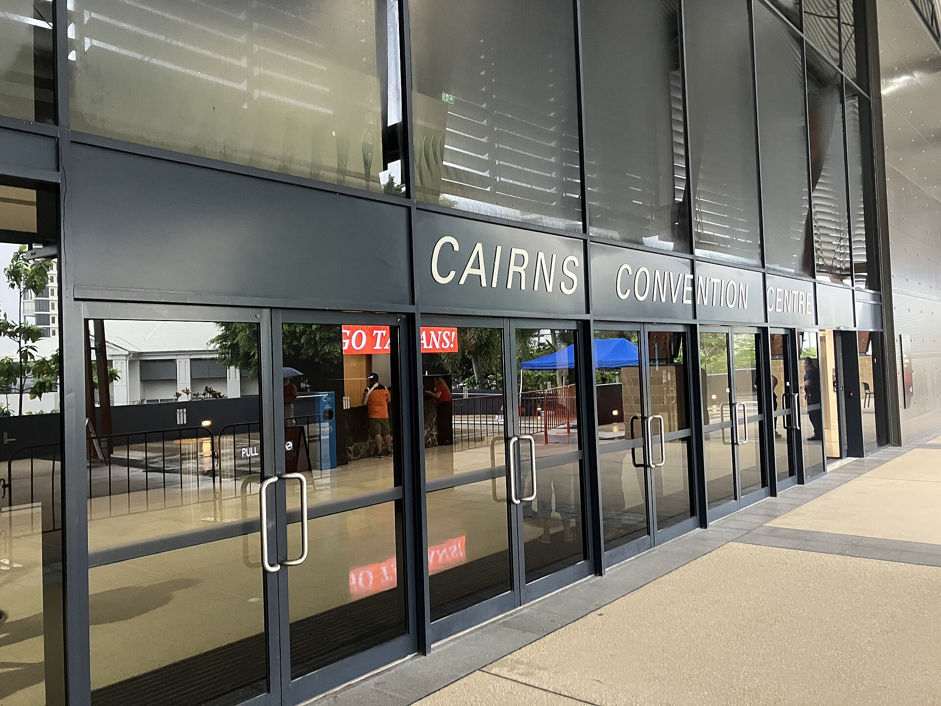 Glass doors and signage at the Cairns Convention Centre arena entrance with a Go Taipans message on a screen inside