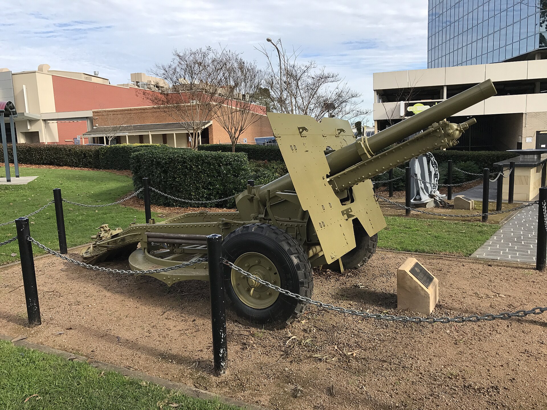 A field gun on display in Mawson Park, Campbelltown, with a tall glass building behind