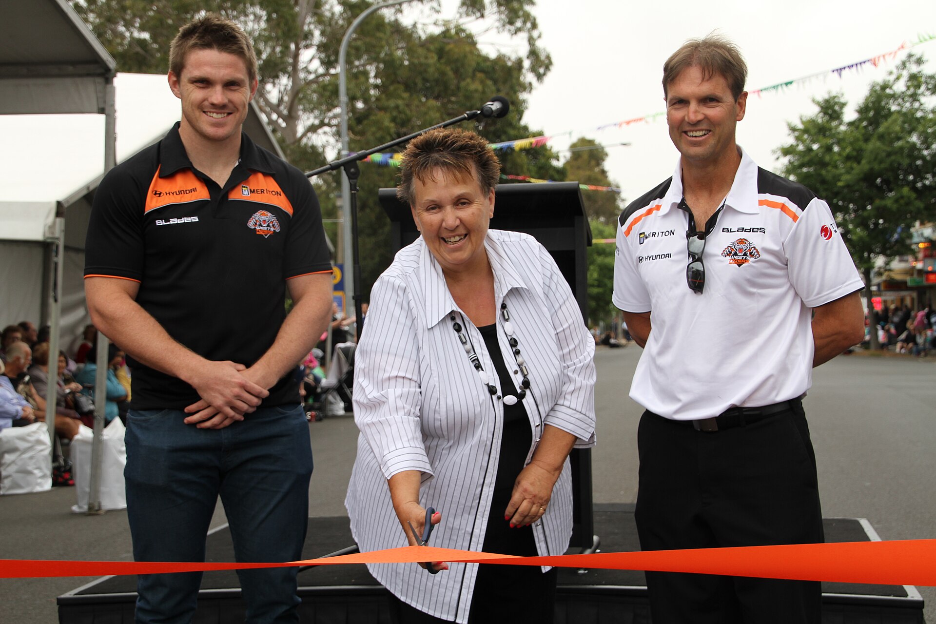 Three people at a ribbon cutting during an earlier Fisher's Ghost street parade in Campbelltown