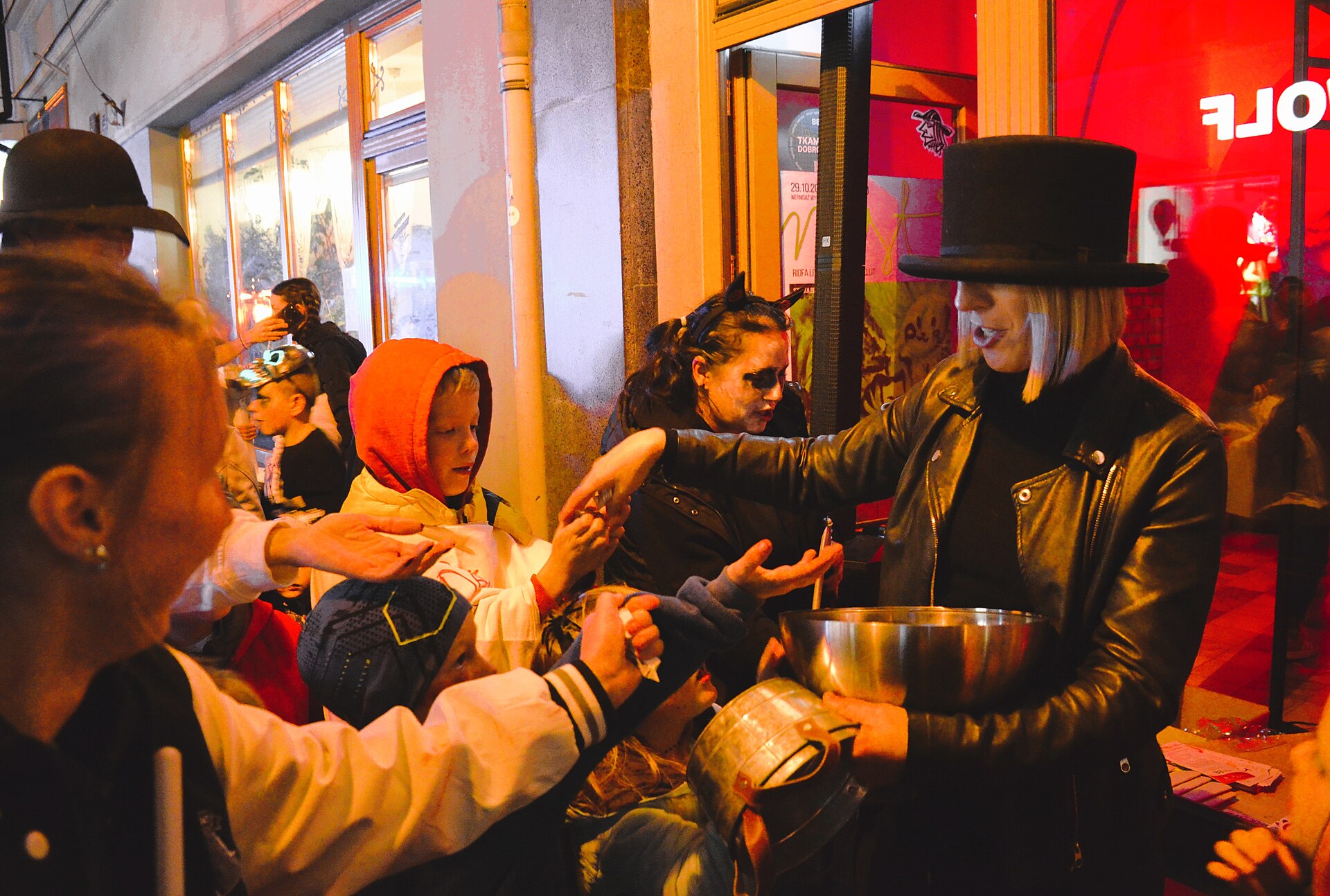 Children and adults in Halloween costumes walking down a main street at a trick-or-treating event in Bielsko-Biała, Poland