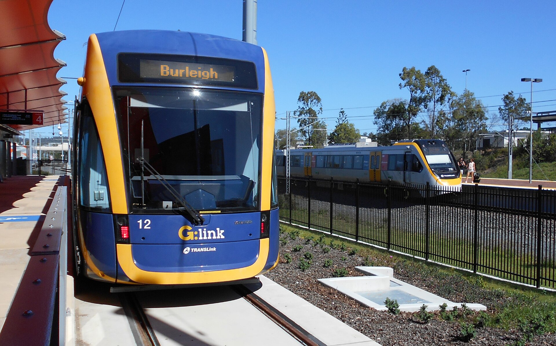 G:link tram at Helensvale station with a Queensland Rail train behind