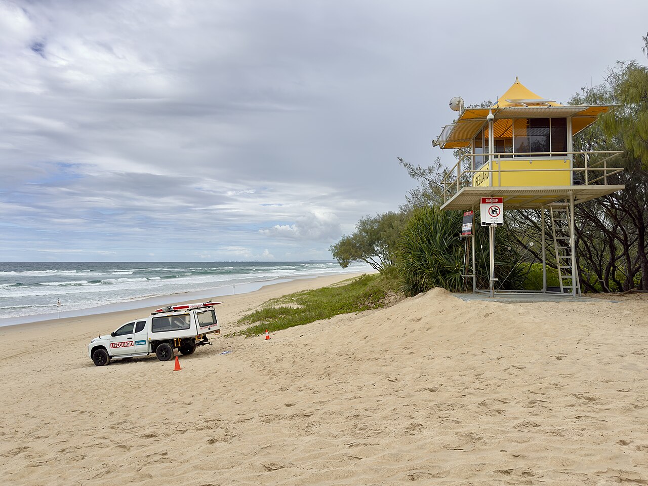 A yellow lifeguard tower and a lifeguard vehicle on The Spit beach, Gold Coast