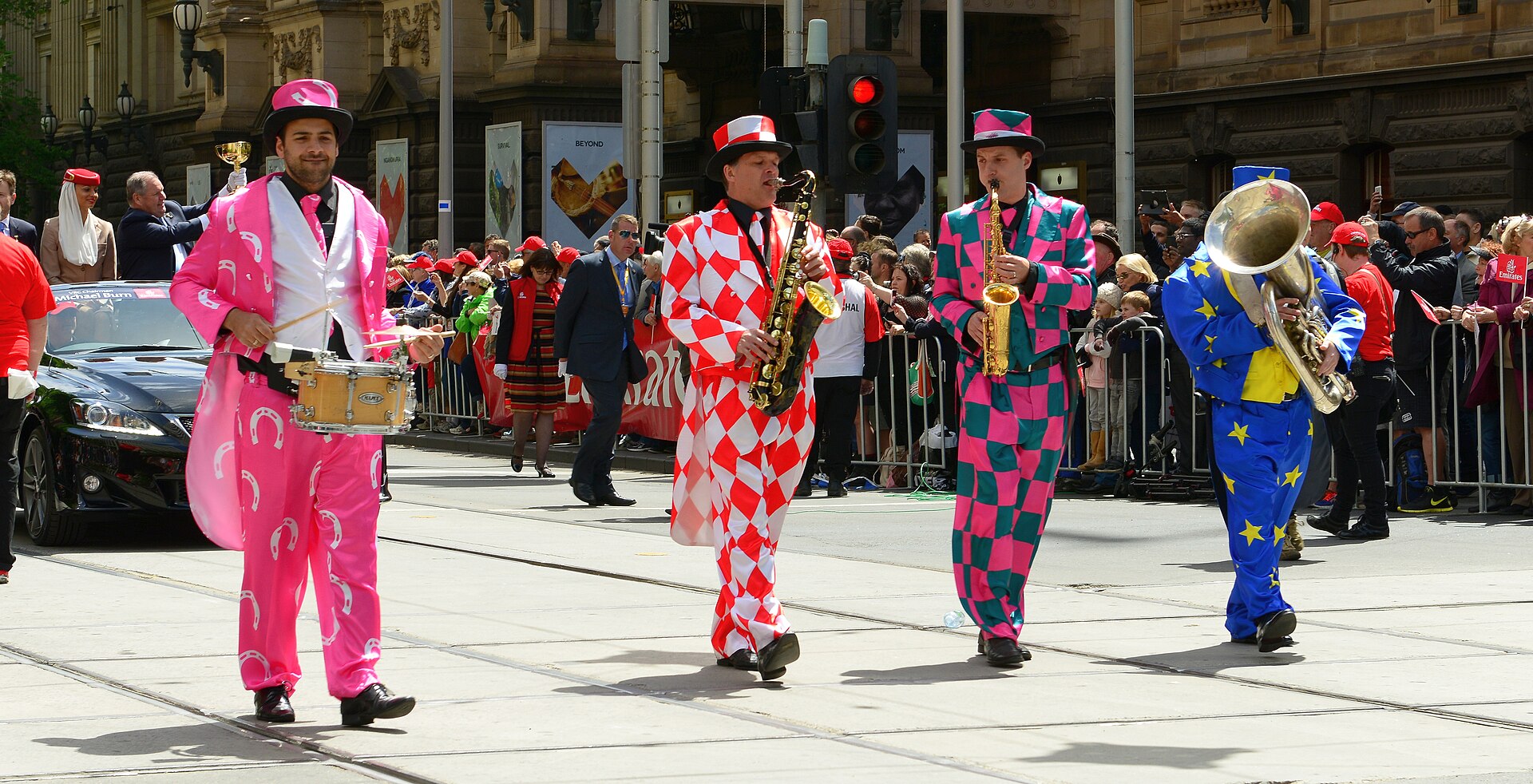 Musicians in pink, red-and-white and blue costumes marching in the 2013 Melbourne Cup Parade through city streets