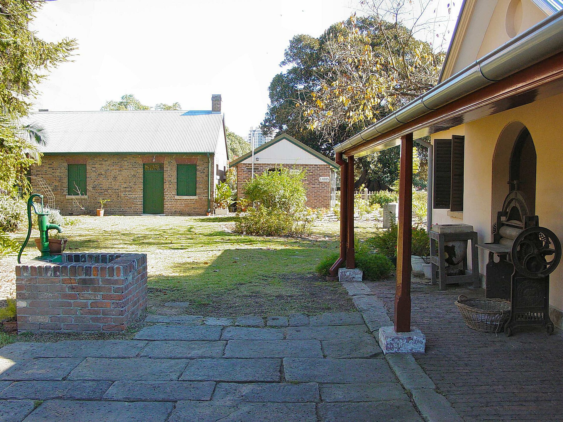 Brick outbuildings and a green hand pump in the grounds of Hambledon Cottage, Parramatta