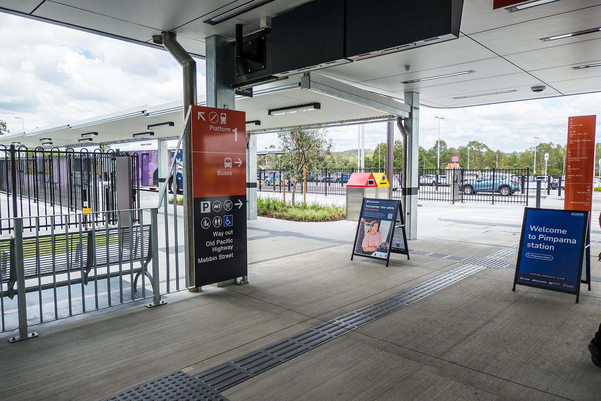 Concourse at Pimpama railway station with signs to platform 1, buses and parking