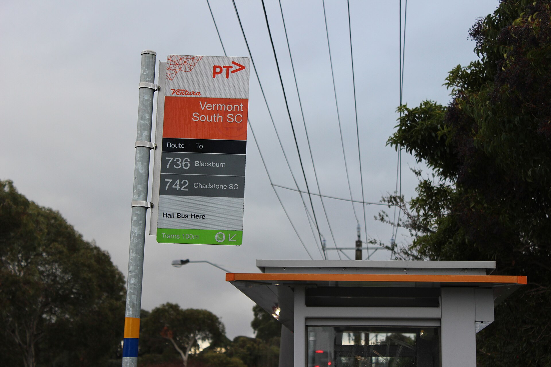 A bus stop sign and shelter at Vermont South Shopping Centre, Victoria, with a note that trams are 100 metres away